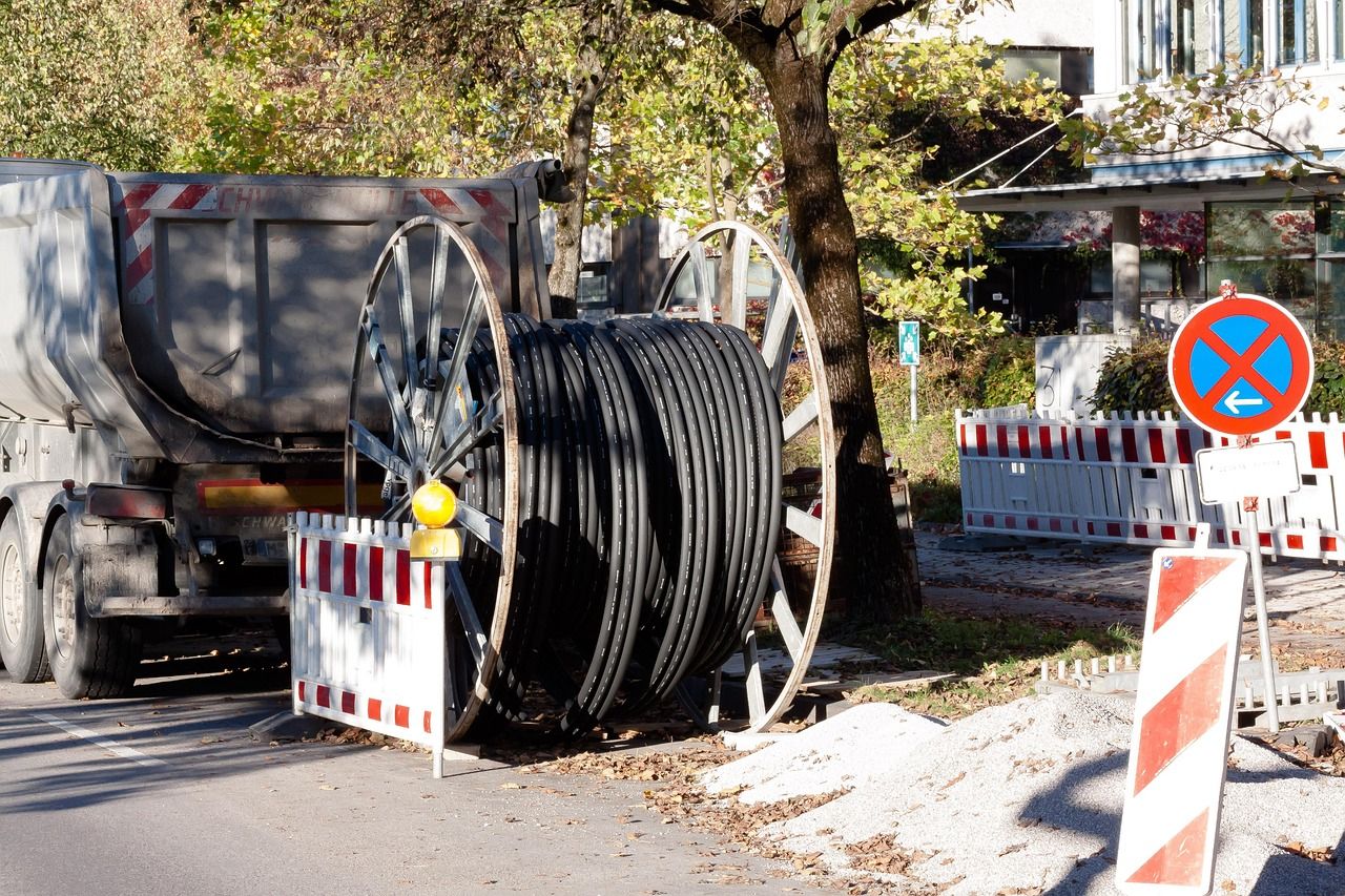 Bęben z czarną rurą kablową przy ogrodzonym placu robót w mieście