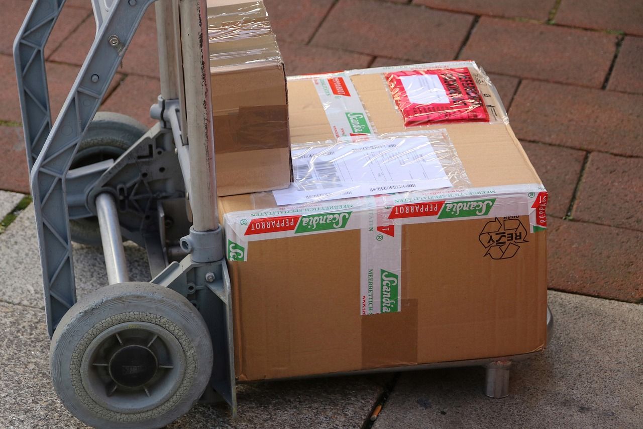 Oklejone kartony na wózku transportowym, gotowe do doręczenia
